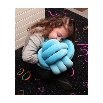A girl holding a blue cuddle ball sensory pillow.