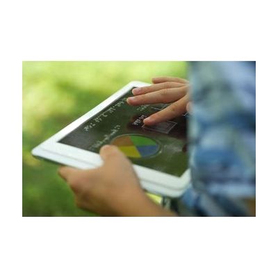 A child outside holding a tablet with an overlay. They are exploring the overlay with their finger.