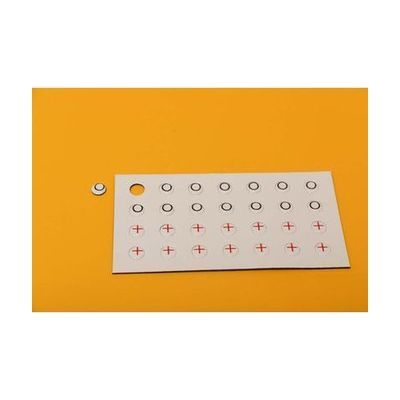 An overhead shot of the red X and black O player token sheet laid on a yellow background.