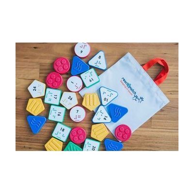 Reach & Match Number Tiles bag filled with multicolored UEB Number Tiles that are spilling out across a wooden surface.