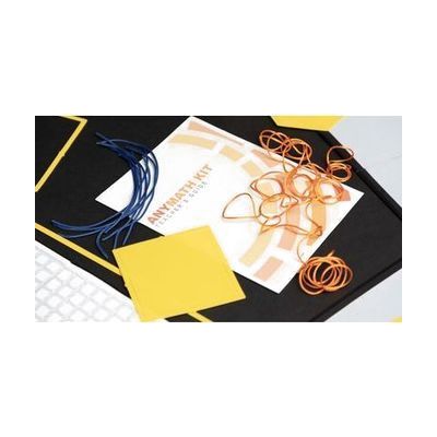 A close-up of the AnyMath Kit print teacher's guide with blue and orange cord arranged on the cover. A square manipulative is placed in the bottom left corner.