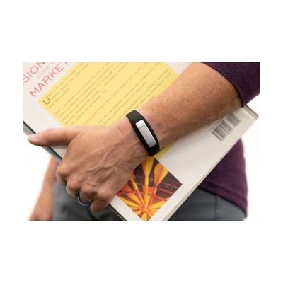 A woman's hand holding a closed book with an OpticAware band on her wrist.