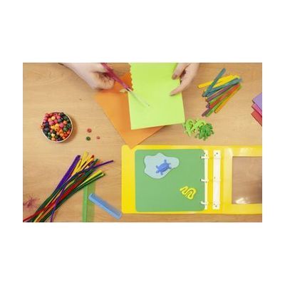 photo shows a pair of hands cutting green paper over a table containing parts from the Tactile and CVI Book Builder kits
