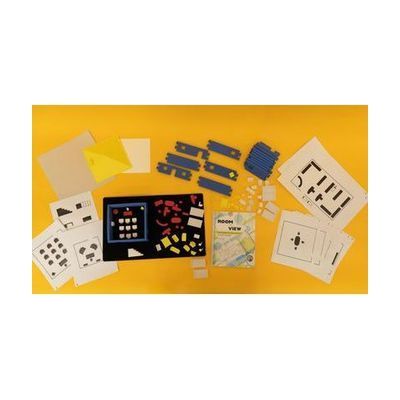 All of the components of the Room With a View kit including tactile graphics, blue foam building block walls, a variety of 3D pieces, and a print guidebook all laid out on a yellow background.