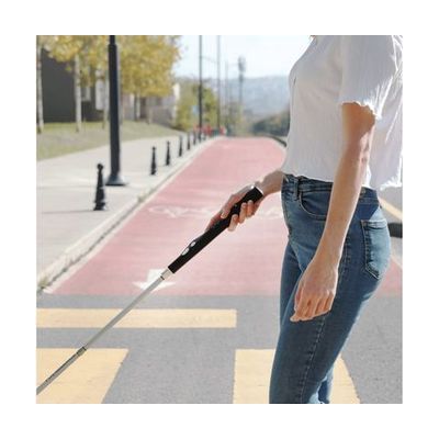 Folding white cane with a black rectangular electronic handle unit at the top, featuring tactile buttons on the grip, approxi