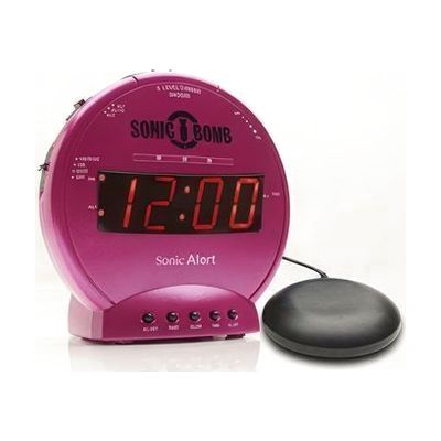 Round pink alarm clock with red control buttons, digital display, and a separate small disc-shaped bed shaker unit connected 