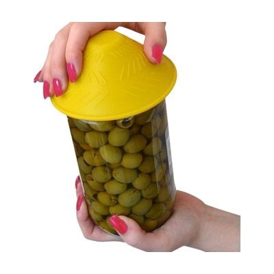 A round yellow silicone grip pad being pressed onto a jar lid by a person's hand.